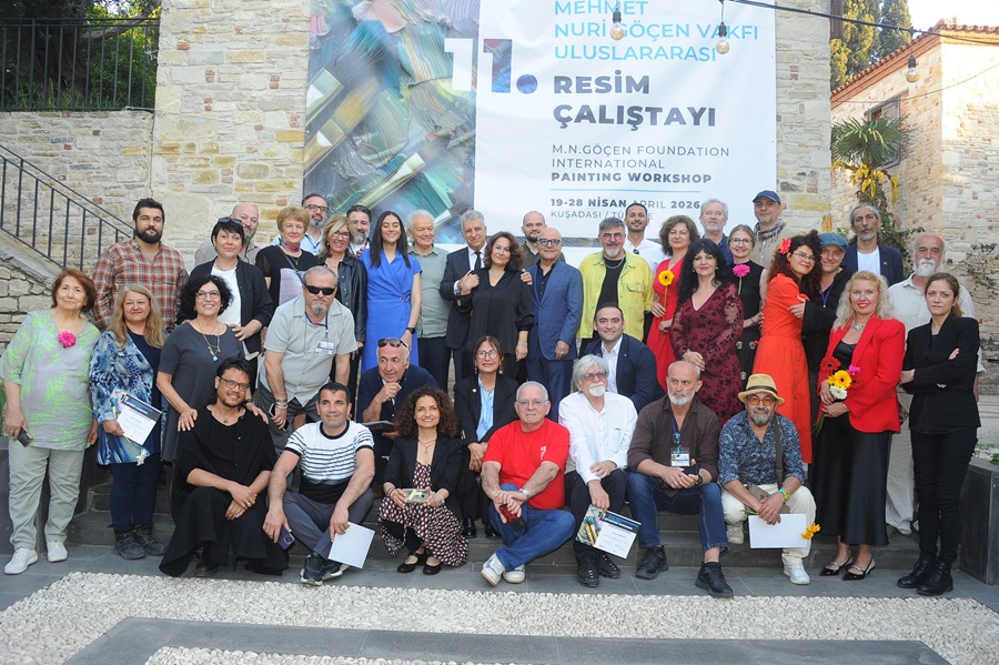 Large diverse group posing on stone steps outdoors in front of a banner advertising the 11th International Painting Workshop.