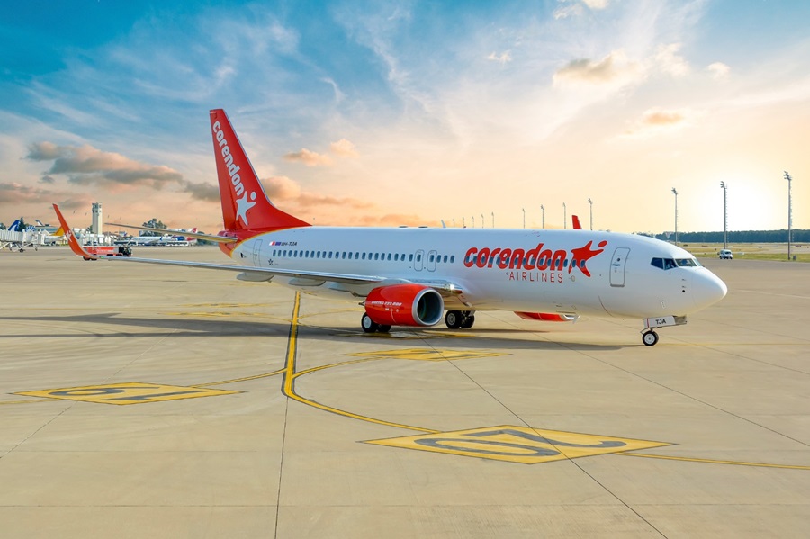Corendon Airlines jet on the tarmac with a red tail and engine, taxiing at sunset against a blue-orange sky.