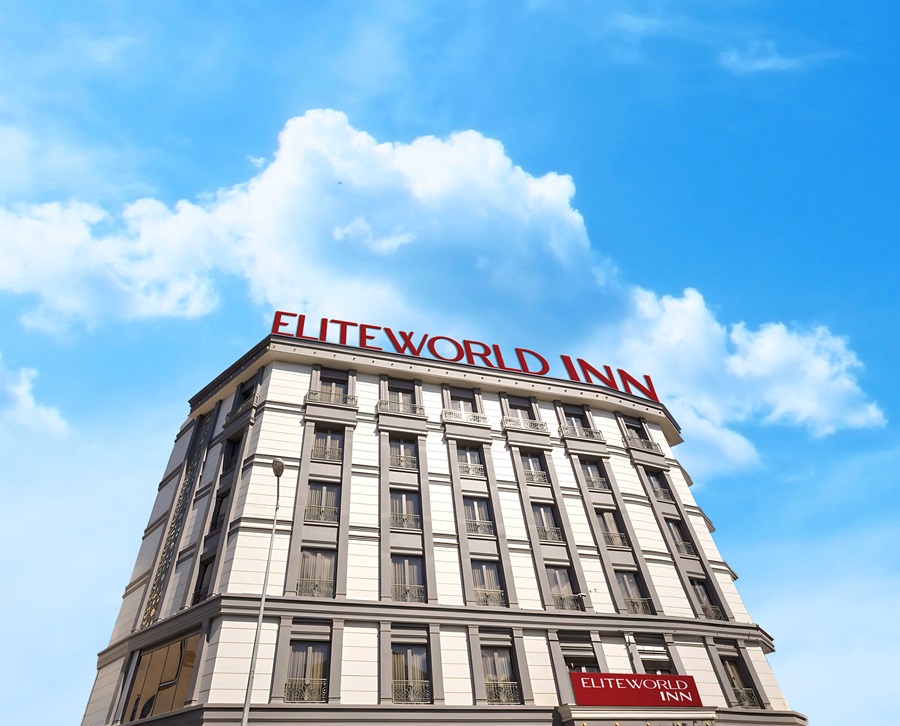 Hotel building with the red 'ELITEWORLD INN' sign atop, set against a blue sky with white clouds.