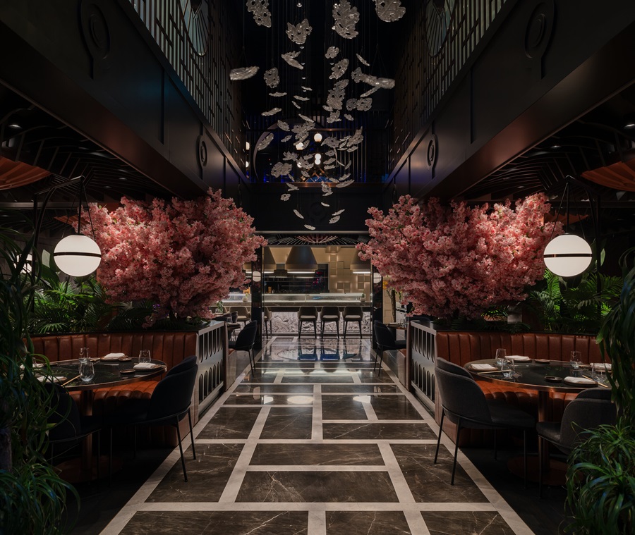 Elegant restaurant interior with pink cherry blossom trees flanking booths and a back bar, marble-tiled floor.