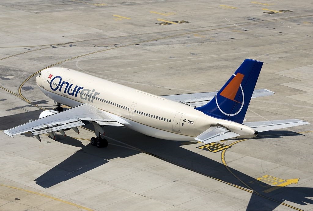Airliner from Onur Air parked on a taxiway, wings extended and ground markings visible