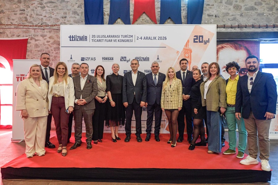 Group of professionals in business attire posing on a red carpet in front of a trade fair backdrop in İzmir, Turkey.