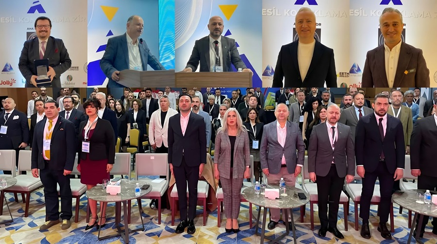 Conference scene: five speakers at podiums on a stage, with a crowd of professionals standing and seated behind them.