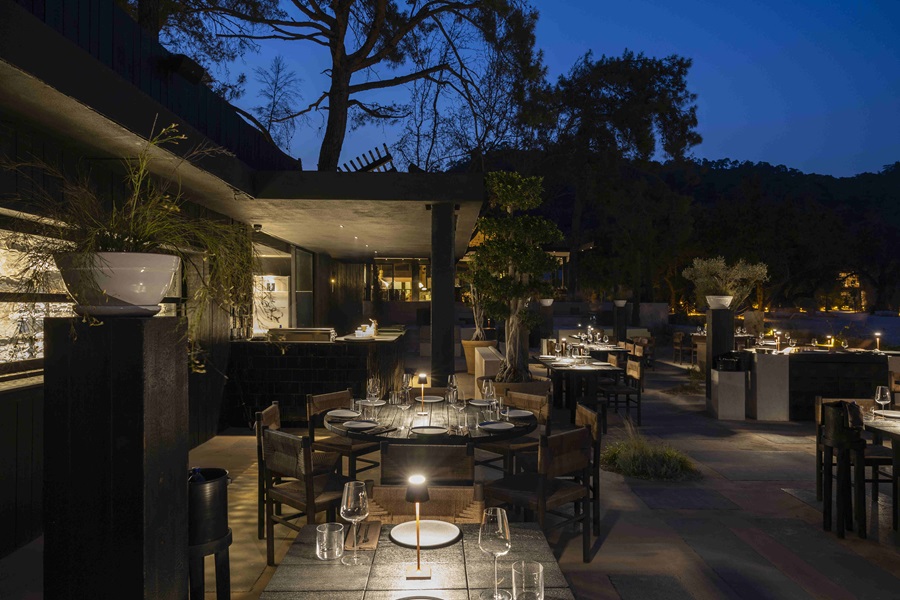 Outdoor restaurant at night with candlelit tables and warm lighting, inviting dining atmosphere.