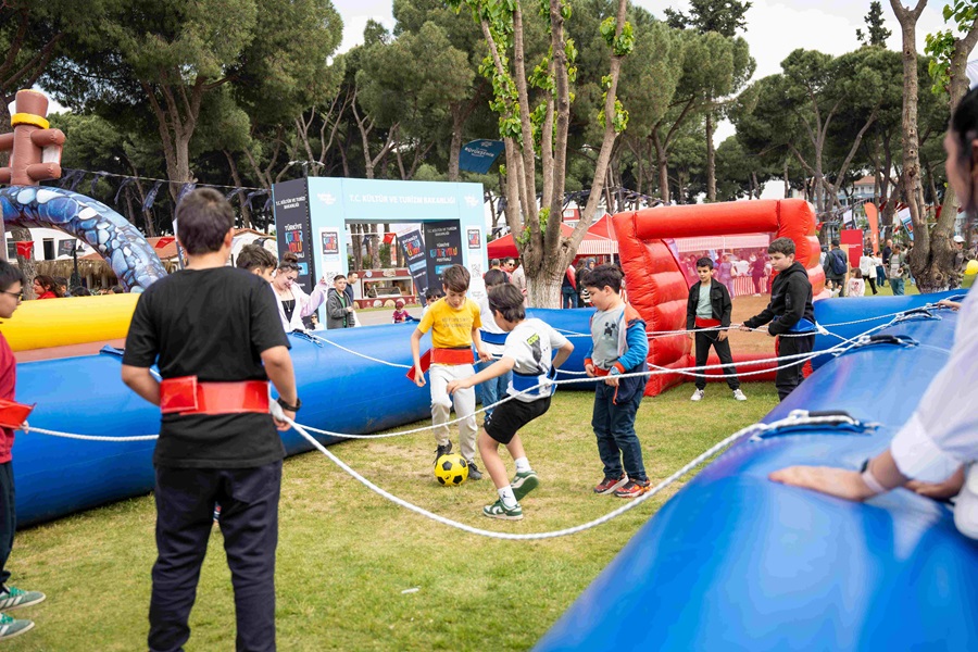 Children playing soccer inside a blue inflatable arena at an outdoor festival or fairground.