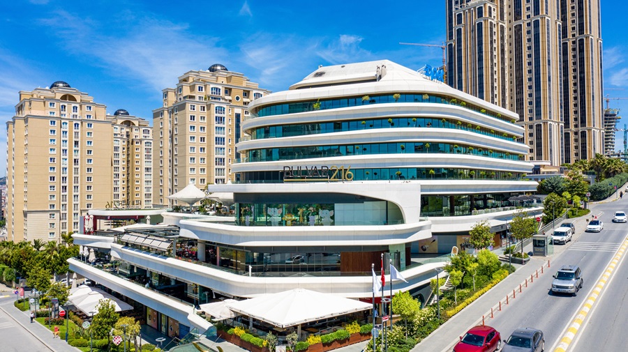 Curved modern shopping complex with terraces, named Bulvar 216, on a busy street beside high-rise buildings.