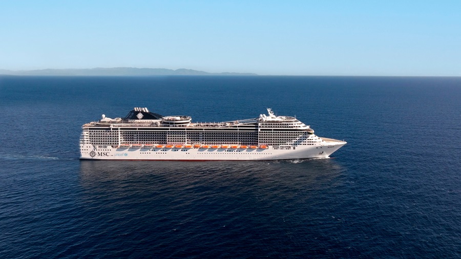 Large white MSC cruise ship sailing on calm blue ocean with a distant horizon and clear sky in the background.