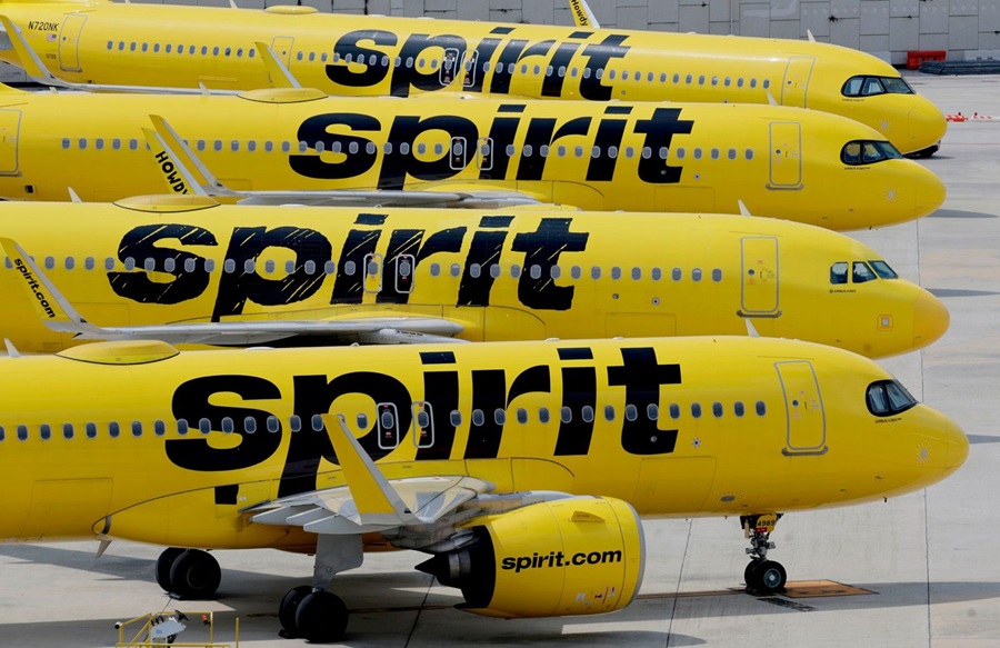 Four yellow Spirit Airlines jets parked on a tarmac, side by side, with bold 'Spirit' branding visible on each fuselage.