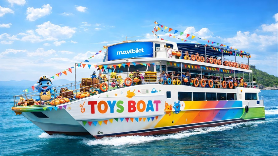 Colorful multi-deck toy-themed tour boat named 'TOYS BOAT' sailing on blue sea with pennant flags and lifebuoys.